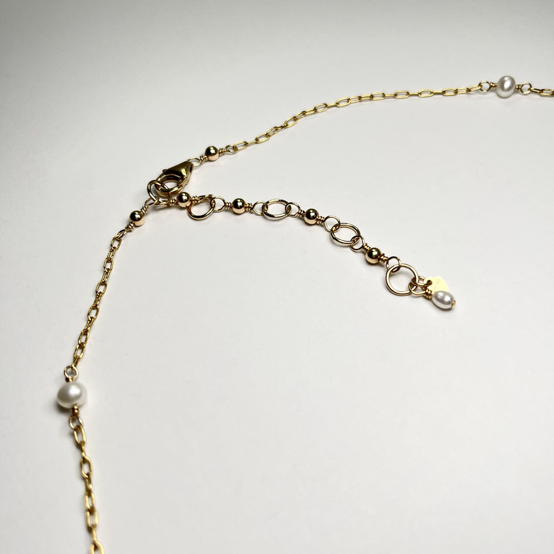 Close-up of a freshwater pearl asymmetrical station necklace in 14K gold-fill staple chain showing clasp and hand-wire-wrapped extender