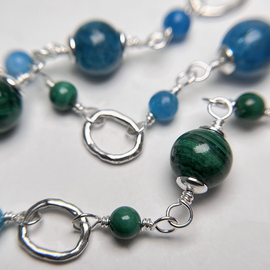 Closeup of gemstone and sterling silver link necklace with deep green malachite and neon blue apatite