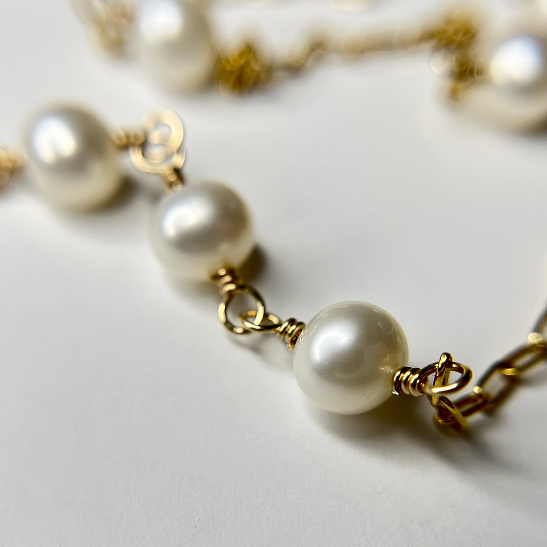 Close-up of a cultured freshwater pearl asymmetrical station necklace in 14K gold-fill staple chain