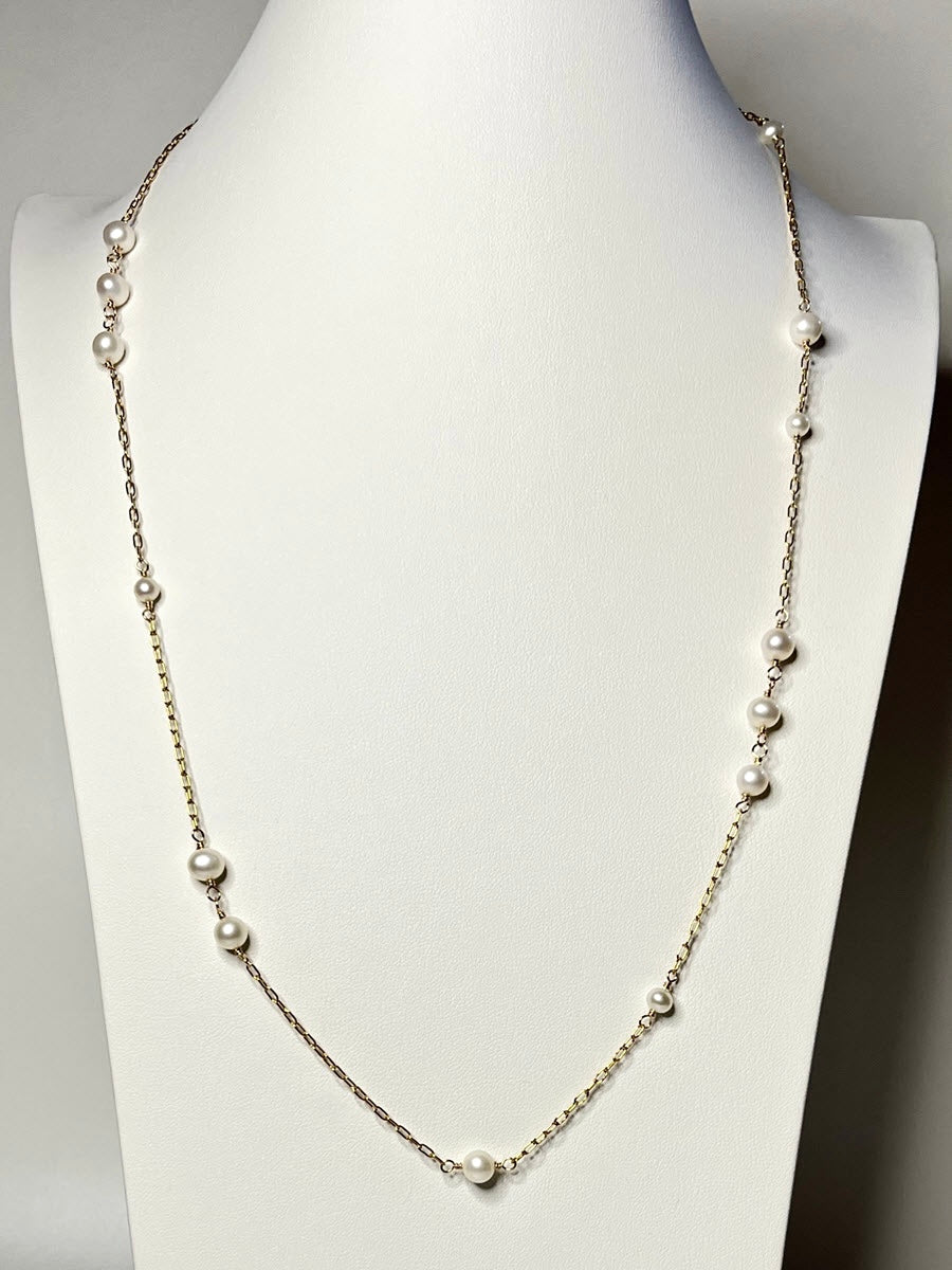 Elegant 14K Gold fill station necklace with asymmetrical pattern of freshwater pearls Shown on neck display