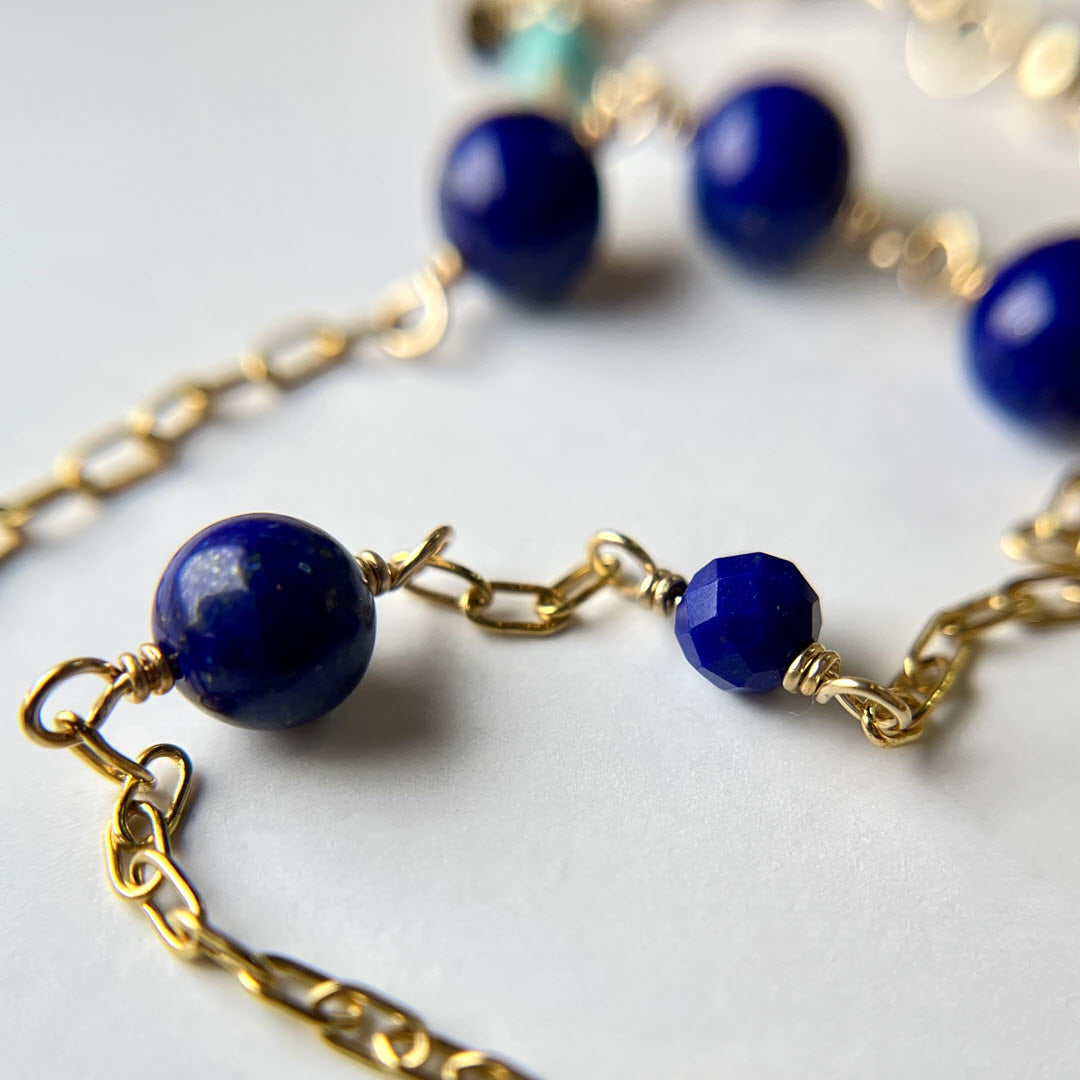 Close-up of a lapis asymmetrical station necklace in 14K gold-fill staple chain 