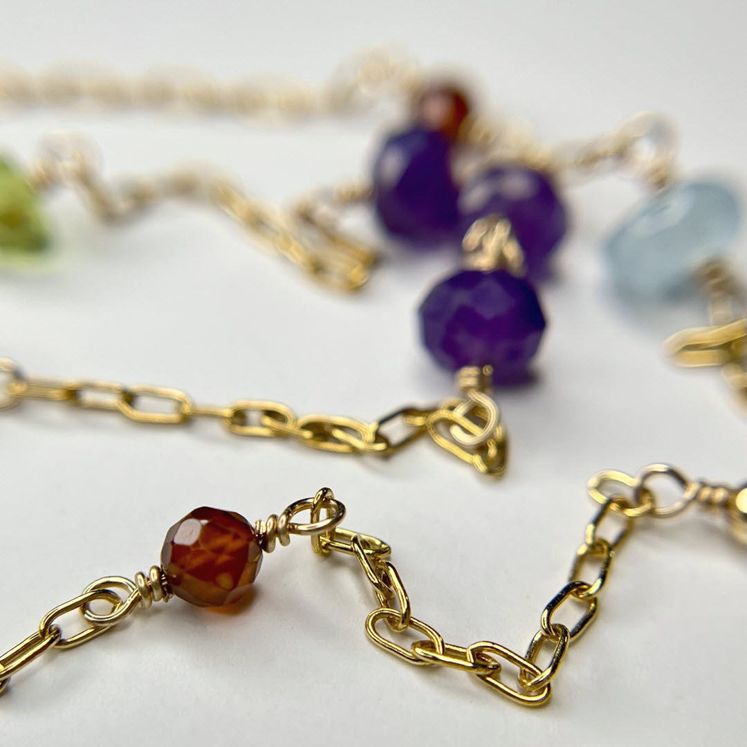 Close-up of a multicolor multi gemstone, asymmetrical station necklace in 14K gold-fill staple chain